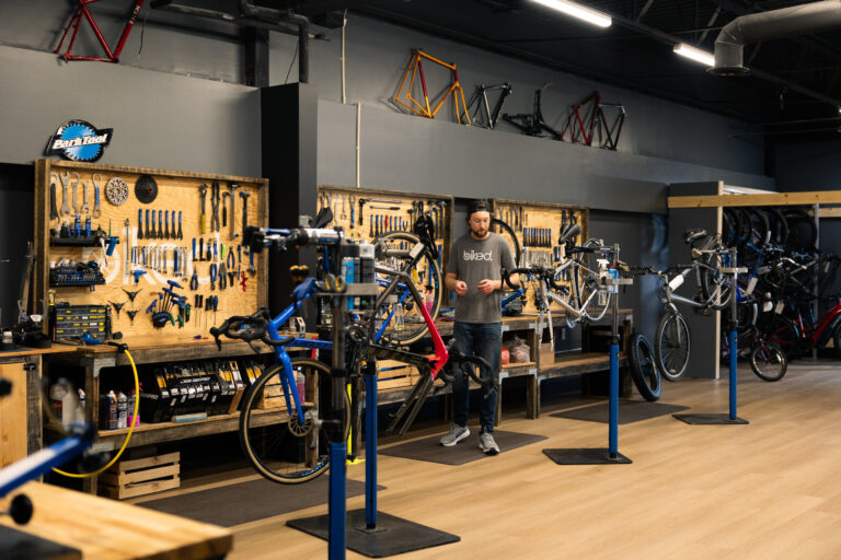 Biked team member working in the Bike shop with several bikes suspended