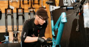 Biked technician working on a bike in the Biked Suspension Lab, with Fox and RockShox forks on the wall behind, in Grand Rapids, Michigan